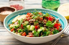 a bowl filled with cucumber, red pepper and green onion salad next to a fork