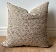 a pillow sitting on top of a wooden floor next to a white wall and wood floor