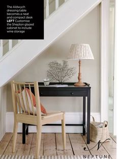 a wooden chair sitting under a stair case next to a table with a lamp on it