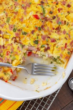 a casserole dish with ham, cheese and vegetables on it next to a fork