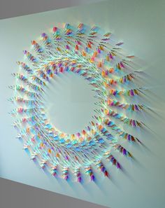 a circular sculpture made out of colorful paper cranes on a wall in an office building