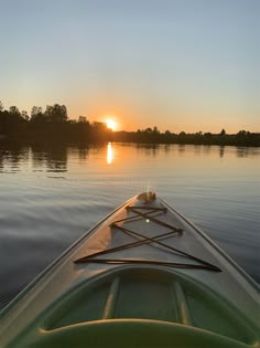 the sun is setting in the distance behind a kayak paddle boat on calm water