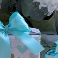 two gift boxes with blue bows and hearts on them are sitting next to each other