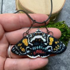 This is a lovely hand painted, Scarlett Tiger moth porcelain pendant. Accents of gold luster and mother of pearl, this pendant is just gorgeous with all the detail. It has a nichrome wire in the top which is then attached to a black waxed cord that is 1.5mm in diameter, 20" in length with an extra 1/2" chain extender. This moth hangs from attached black chain from the nichrome wire at the top of each wing. Will come in a jewelry gift box, ready for gift giving! Unique Black Enamel Pendant Necklace, Artistic Hand Painted Enamel Necklaces, Artsy Handmade Black Necklace, Hand Painted Butterfly Jewelry Gift, Hand Painted Black Polymer Clay Jewelry, Hand Painted Butterfly Jewelry For Gift, Hand Painted White Pendant Jewelry, Artistic Black Enamel Jewelry, Black Wearable Art Jewelry As Gift