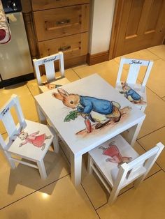 two children's wooden chairs and table with peter rabbit painted on the top one