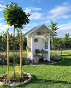 a small white shed sitting on top of a lush green field