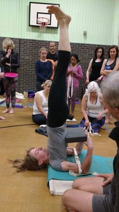 a group of people are doing yoga in a gym with one person upside down on the floor