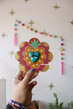 a person holding up a paper flower in front of a wall