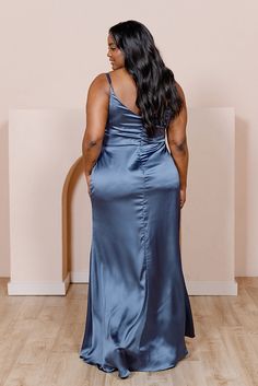 a woman in a blue dress standing on a hard wood floor with her back to the camera