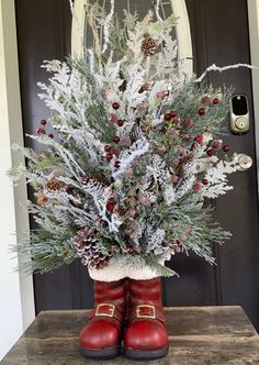 a red boot is sitting in front of a door decorated with pine cones and berries