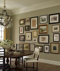 a dining room table with chairs and pictures on the wall