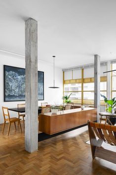 a living room filled with furniture and wooden flooring next to tall windows on either side of the wall