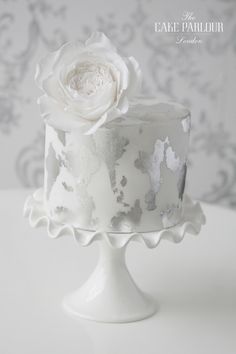 a cake with white frosting and a flower on top is sitting on a table