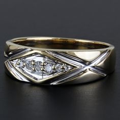 a gold ring with two diamonds on top and an x design in the middle, sitting on a black surface