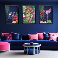 a living room with blue walls and pink furniture, paintings on the wall above couches