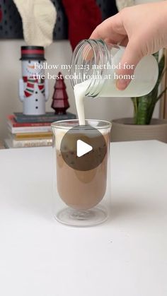 a person pouring milk into a glass on top of a table