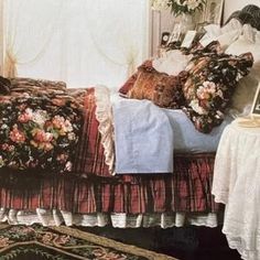 a bed sitting in a bedroom next to a window covered in pillows and blankets on top of a rug