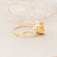 a yellow diamond ring sitting on top of a wooden table