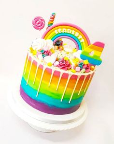 there is a rainbow cake with white icing and candy toppings on the top