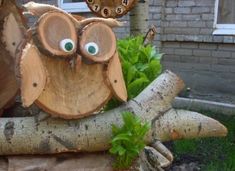 an owl statue sitting on top of a tree stump in front of a house with eyes painted on it