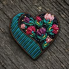 a heart shaped beaded brooch sitting on top of a wooden table