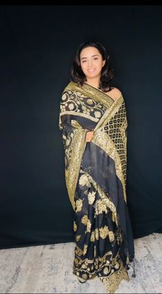 Indulge in timeless elegance with our exquisite Black Banarasi Khaddi Georgette Saree, adorned with lustrous gold zari. This masterpiece seamlessly blends traditional artistry with contemporary sophistication. Crafted from the finest Khaddi Georgette, the saree drapes effortlessly, creating a graceful and ethereal silhouette. The classic black hue serves as the perfect canvas for the intricate gold zari work, which adds a touch of opulence and glamour. Handwoven by skilled artisans, this saree showcases the rich heritage of Banaras. The delicate interplay of light and shadow created by the gold zari on the black base results in a mesmerizing visual effect. Perfect for evening soirees, weddings, or any special occasion where you desire to make a lasting impression. Fabric: Pure Khaddi Georg Gold Brocade Pre-draped Saree With Zari Weaving, Gold Brocade Pre-draped Saree With Zari Work, Transitional Gold Banarasi Silk Pre-draped Saree, Traditional Formal Chanderi Pre-draped Saree, Gold Pre-draped Jamawar Saree With Zari Work, Traditional Gold Pre-draped Saree With Self Design, Semi-stitched Brocade Pre-draped Saree With Zari Work, Elegant Gold Pre-draped Saree For Festivals, Semi-stitched Gold Banarasi Silk Traditional Wear