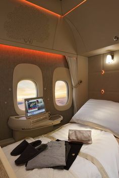 an airplane bed with two laptops on top of it and some pillows in front of the window