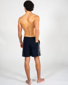 a man with no shirt standing in front of a white background wearing black swim trunks