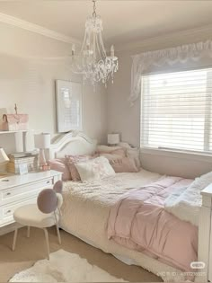 a bedroom with a bed, dresser and chandelier hanging from it's ceiling