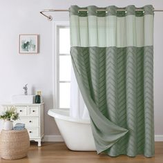 a bath tub sitting next to a window in a bathroom under a green shower curtain