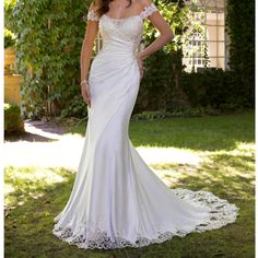 a woman in a white wedding dress standing under a tree with her hands on her hips