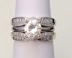 a white gold ring with an oval cut diamond and pave set diamonds on each band