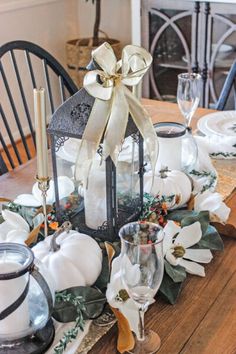 a wooden table topped with white pumpkins and candles