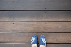 a person standing on top of a wooden floor wearing blue and white shoes with an arrow painted on them