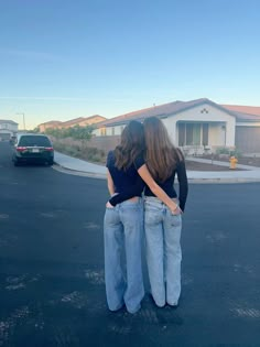 two women standing in the middle of a parking lot with their backs to each other