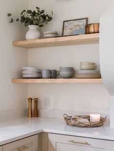 the shelves in this kitchen are filled with plates and bowls, vases and candles