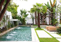 an outdoor pool surrounded by palm trees and water features two lounge chairs facing the pool