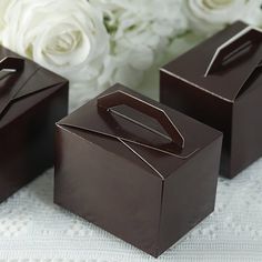 three chocolate boxes sitting on top of a table next to white flowers and greenery