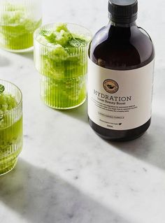 three glasses filled with green liquid sitting next to each other on top of a table