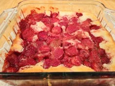 a glass casserole dish with strawberries in it on a wooden table top