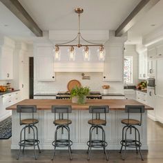 a large kitchen island with four stools in front of it and a center island