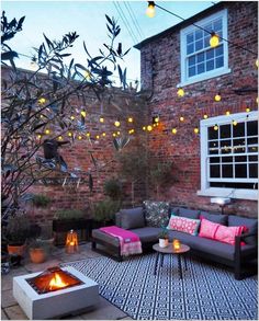 an outdoor living area with couches, fire pit and potted plants