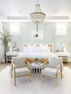 a bedroom with two chairs, a bed and a chandelier hanging from the ceiling