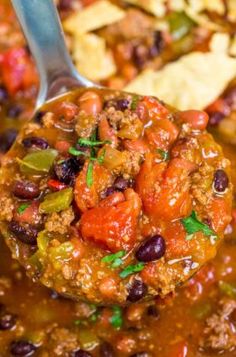 a ladle full of chili and beans with tortilla chips in the background