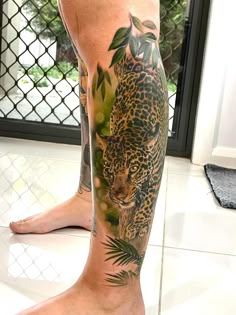 a man with a tattoo on his leg that has a leopard and leaves on it