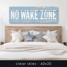 a wooden sign that says no wake zone on the wall above a bed with pillows