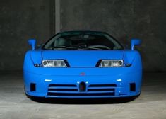 a blue sports car parked in a parking garage next to a wall and concrete floor