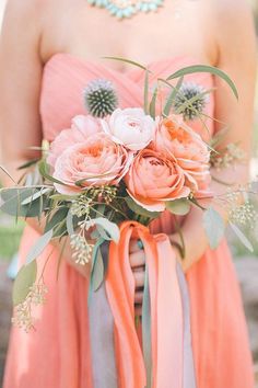 a woman in an orange dress holding a bouquet with flowers on it's side