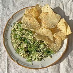 a white plate topped with guacamole and tortilla chips on top of a table