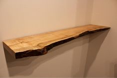 a wooden shelf sitting on top of a white wall